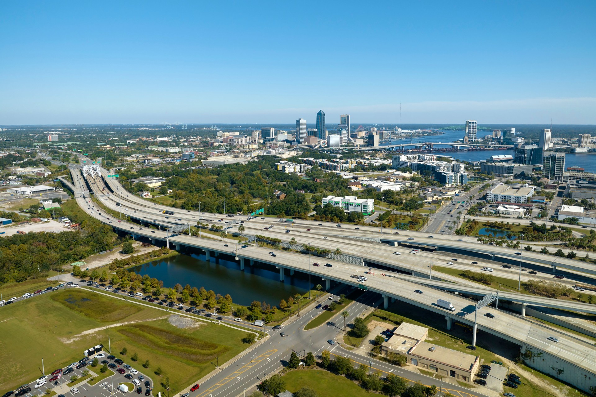 Aerial view of Jacksonville city with high office buildings and american freeway intersection with fast moving cars and trucks. USA transportation infrastructure concept