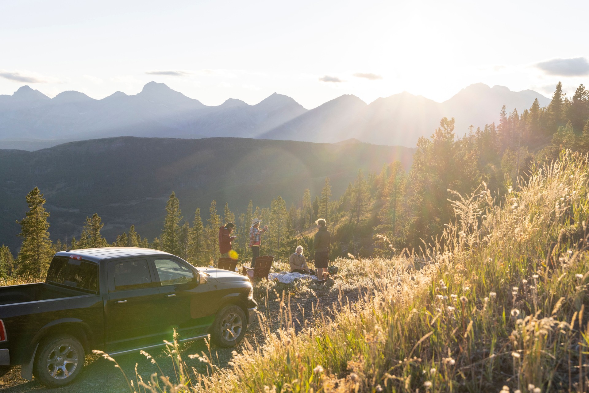 Family with adult offspring enjoy picnic on mountain meadow